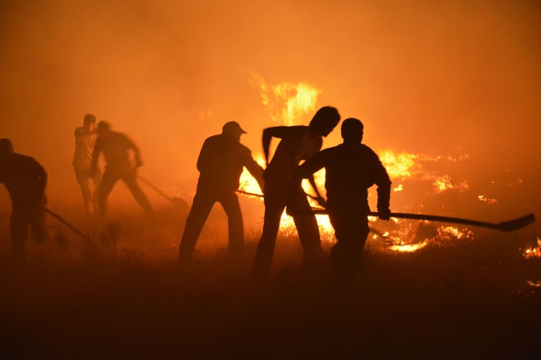 Silhouetted firefighters battling wildfire at night