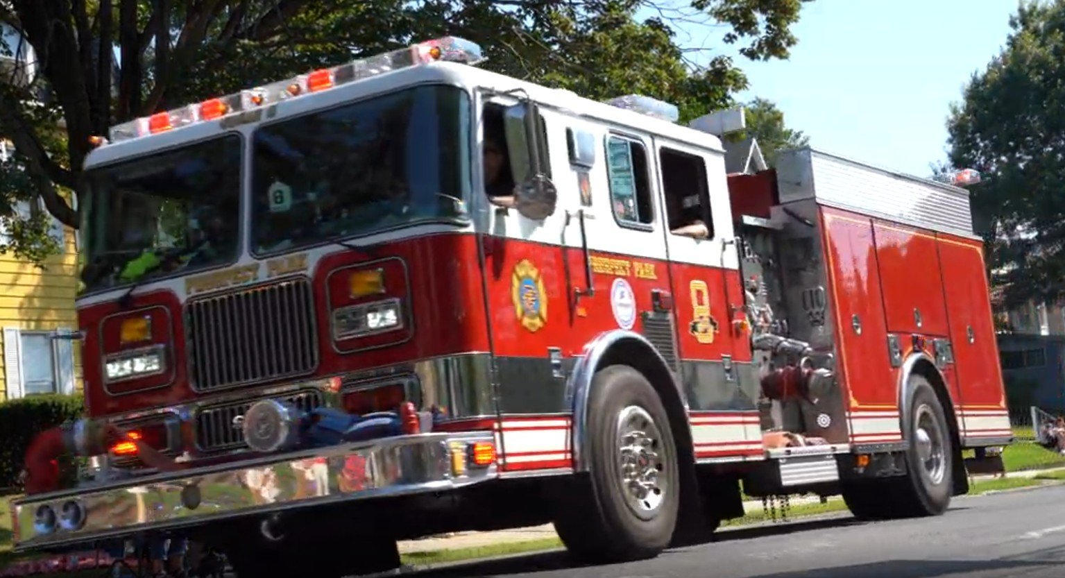 Red and white fire truck parked on a residential street with trees in the background