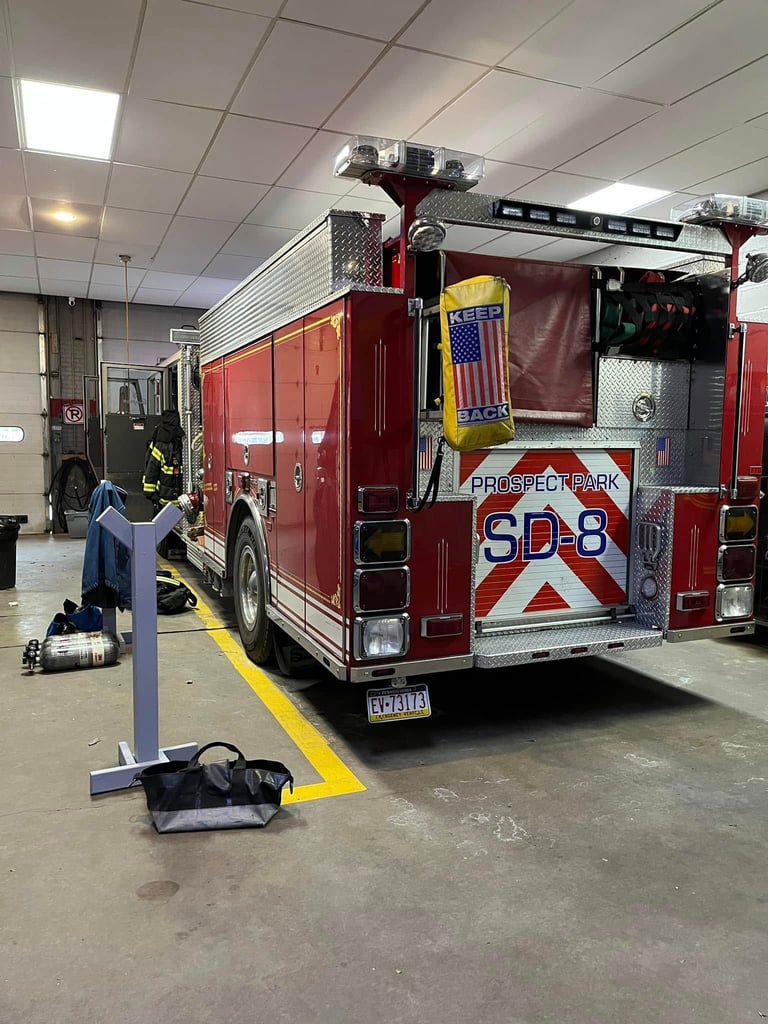 Red fire engine numbered SD-8 parked in indoor facility with firefighter equipment visible on ground