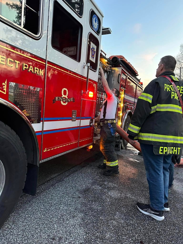 Firefighters in reflective gear standing beside red fire trucks during daytime operations