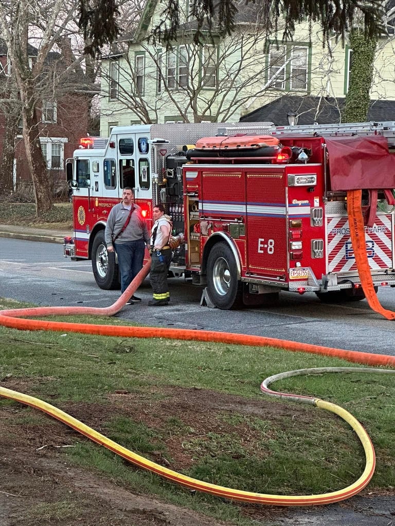 Fire department Engine 8 with firefighters connecting water hoses during a residential fire response operation